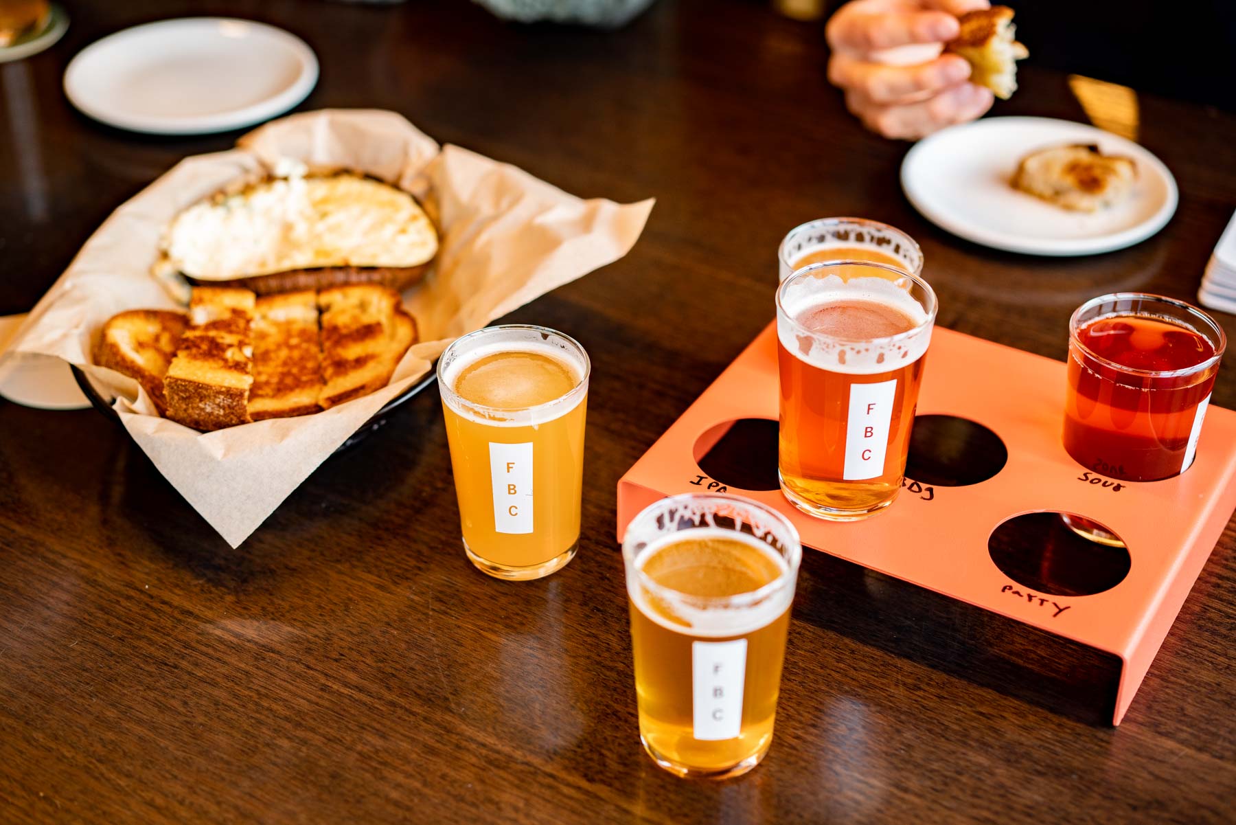 A beer flight and a basket of grilled cheese on a wood table at a Hood River brewery