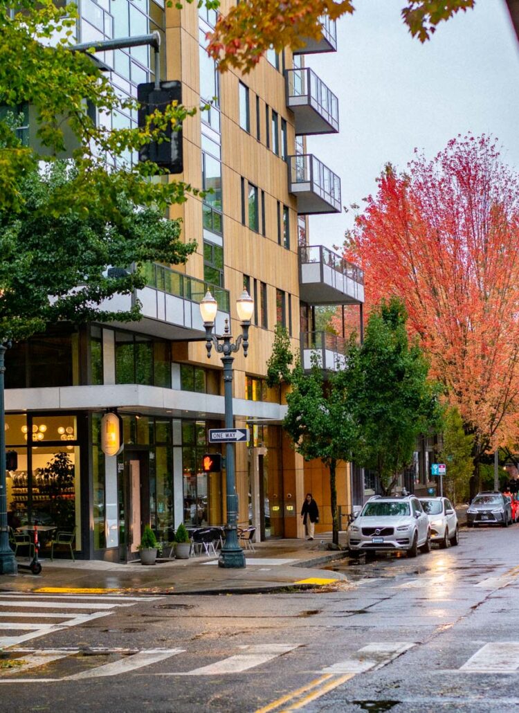 Wet Pearl District street corner in Portland with red fall maples and lit street lamps